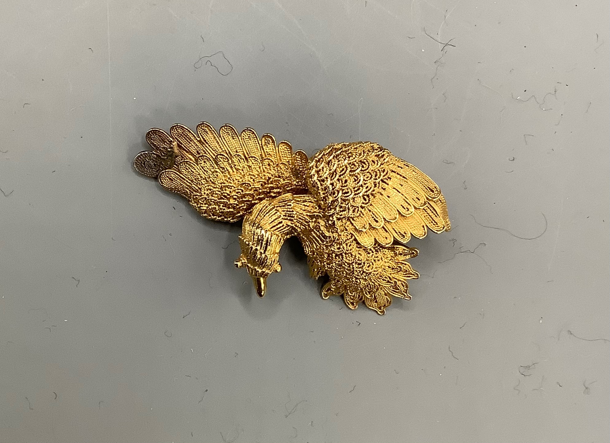 A Chinese filigree yellow metal eagle brooch, stamped 'WS 20 (with character marks)', 36mm, gross 6.5 grams.